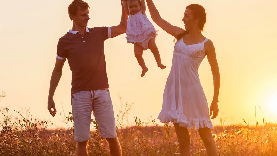 A kid being help up by their parents