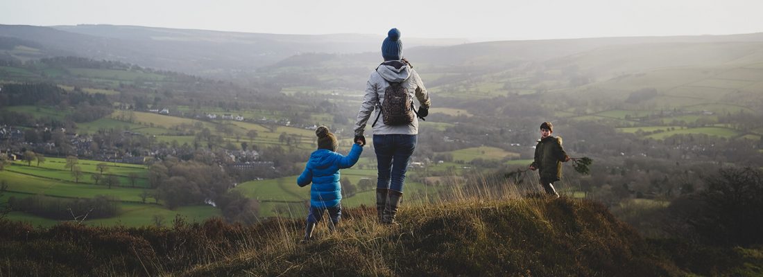 A parent and two kids walking in the hills