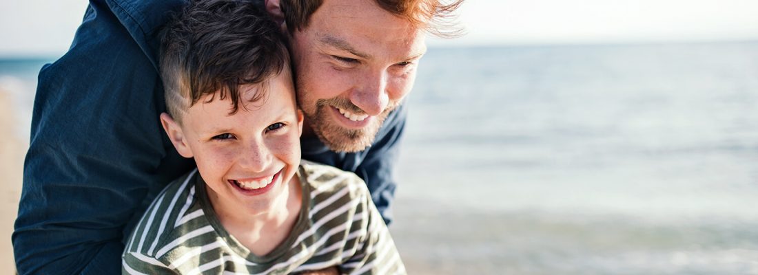 A kid and his dad playing on the beach