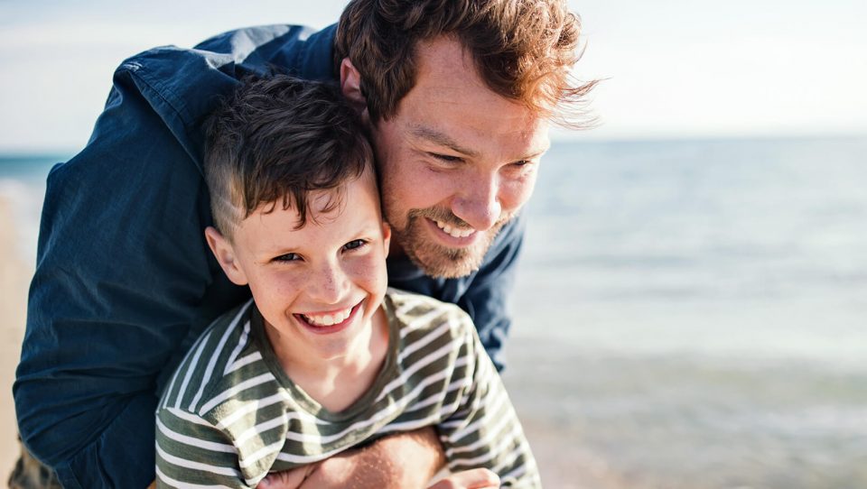 A kid and his dad playing on the beach