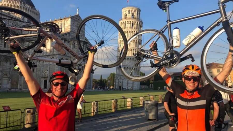 Two people lifting their bikes above their head