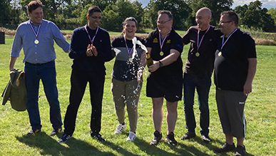 A group of people popping open a bottle of champagne