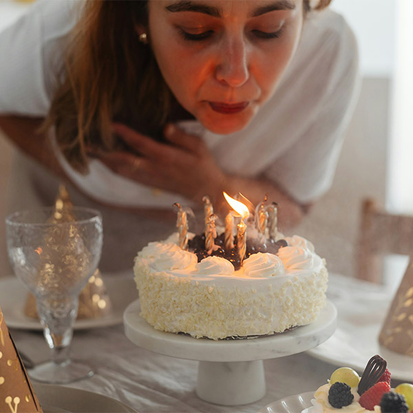 Lady blowing out candles on a cake